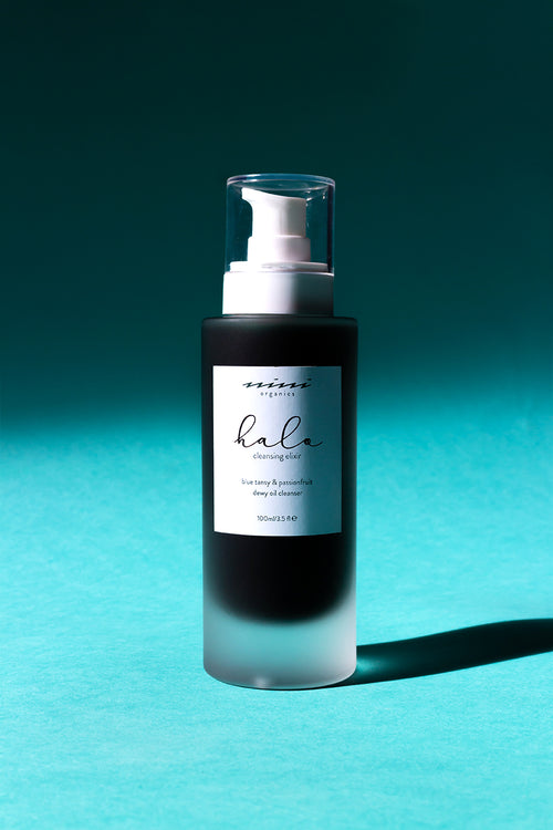 Elixir nettoyant bio de chez Nini Organics dans un flacon pompe en verre transparent de 100 ml, qui laisse apparaître la couleur verte du soin